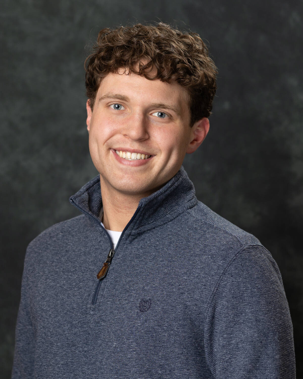 Student wearing a quarter zip posing for a studio headshot